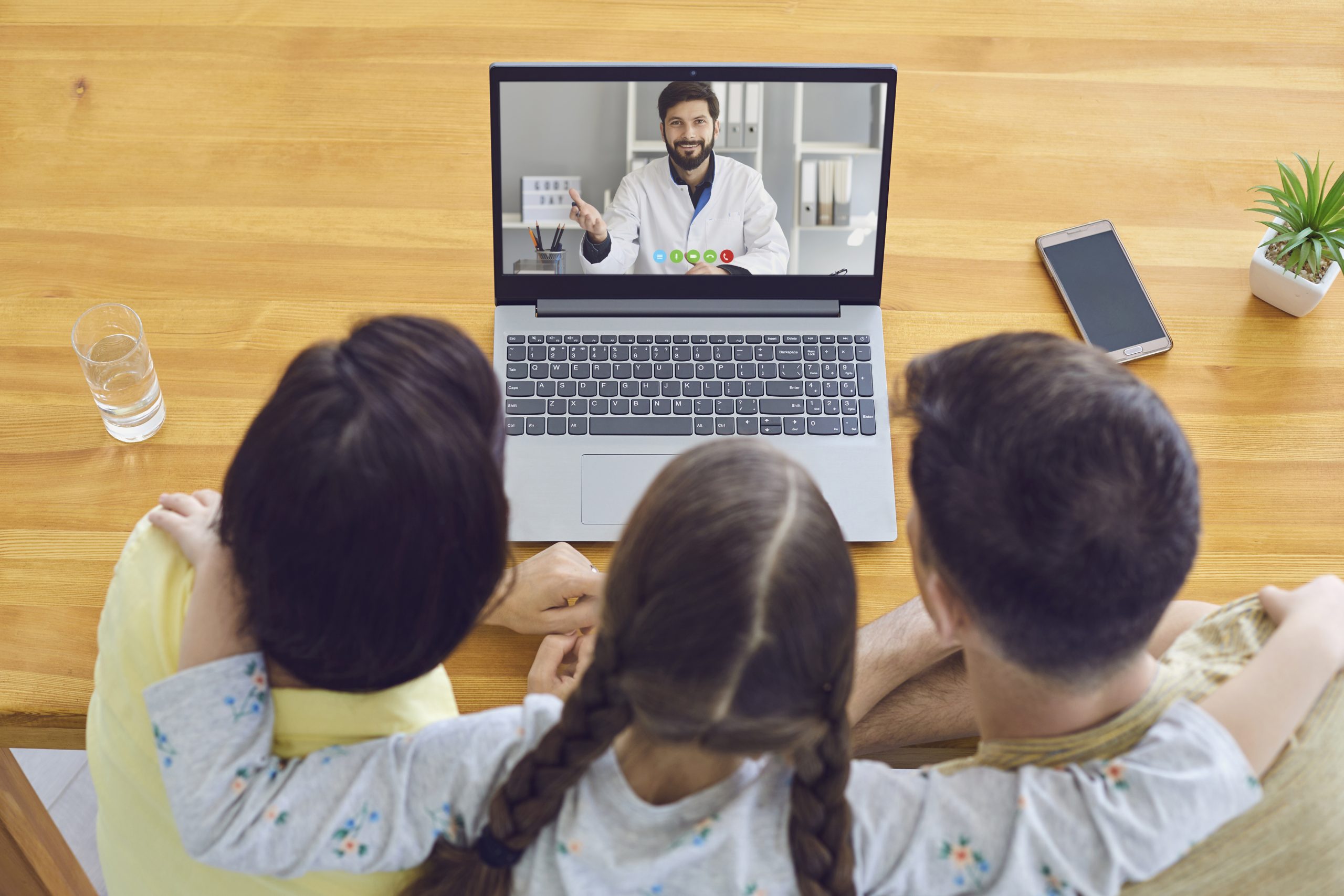 Family doctor call online.Parents and a child consult a doctor using a laptop at home. Online medical consultation.